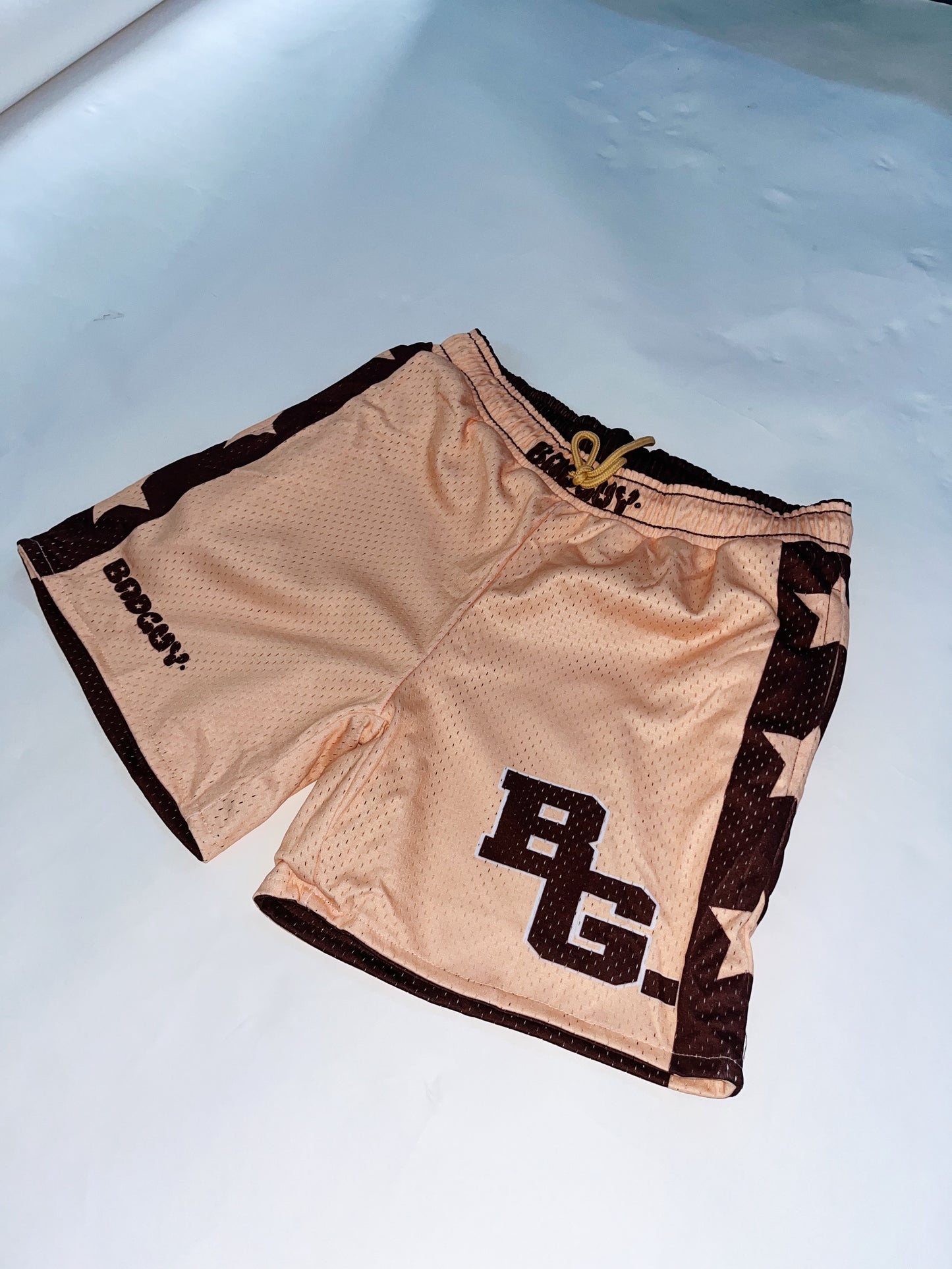 Reversible Allstar 2.0 mesh shorts in peach beige and brown with bold star designs, featuring an elastic waistband and practical pockets, suitable for men and women, ideal for basketball and workouts.